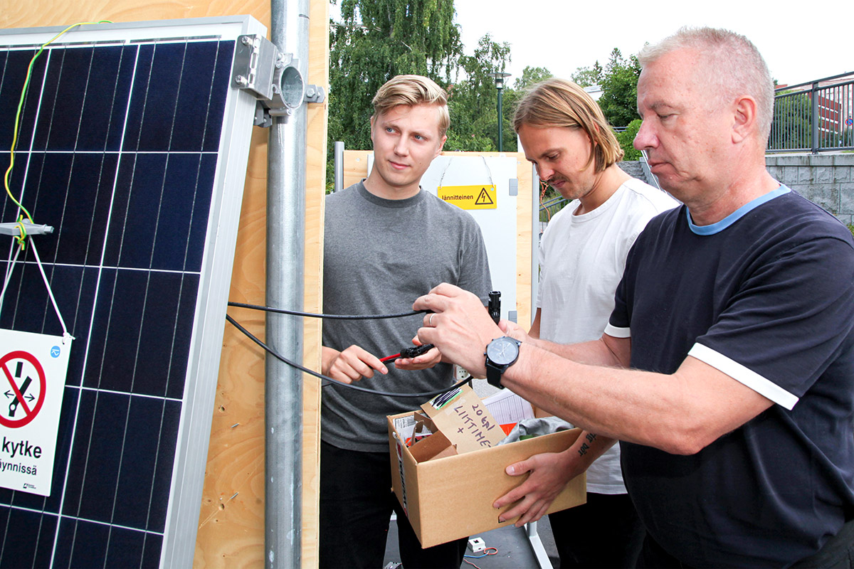 Sähköinfon tekninen johtaja Esa Tiainen tarkasti yhdessä talon kesätyöntekijöiden, Metropolia-ammattikorkeakoulussa sähkö- ja energiatekniikkaa opiskelevien Ville Alakärpän ja Sampo Kivelän kanssa, että talon aurinkosähköjärjestelmien asennuskursseilla käytettävät harjoituslaitteet vastaavat standardin uusia vaatimuksia. Kuva Mikko Arvinen.